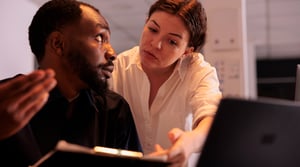 analyst-helping-colleague-analyzing-report-compar-2023-03-31-18-00-52-utc